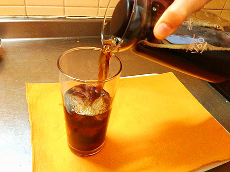 グラスからコップにコーヒーを注ぎ込む