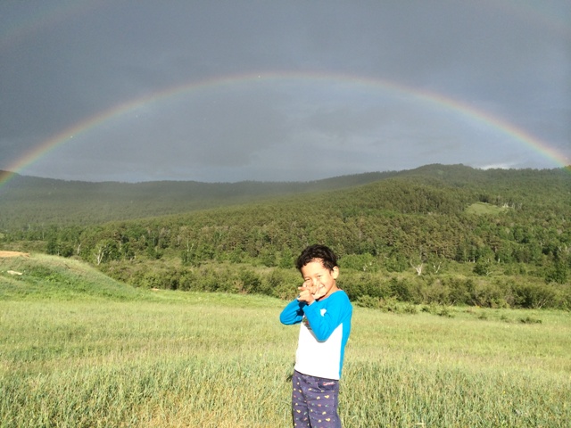 大きな虹を背にポーズする子供たち